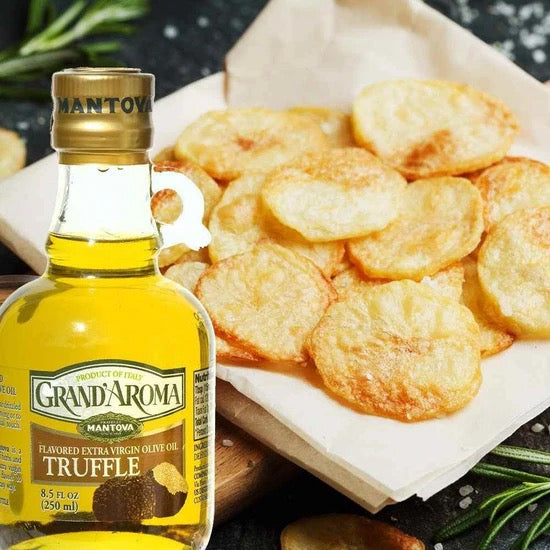 Bottle of Grand'Aroma Truffle olive oil with fried truffle chips on a wooden board.